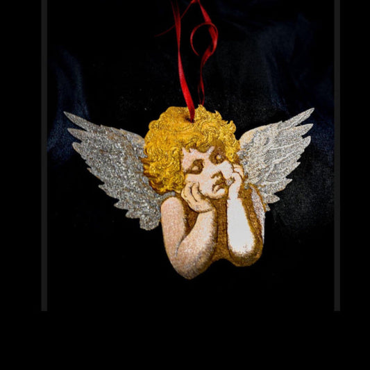 Decorative angel ornament with wings and a red ribbon on a dark background
