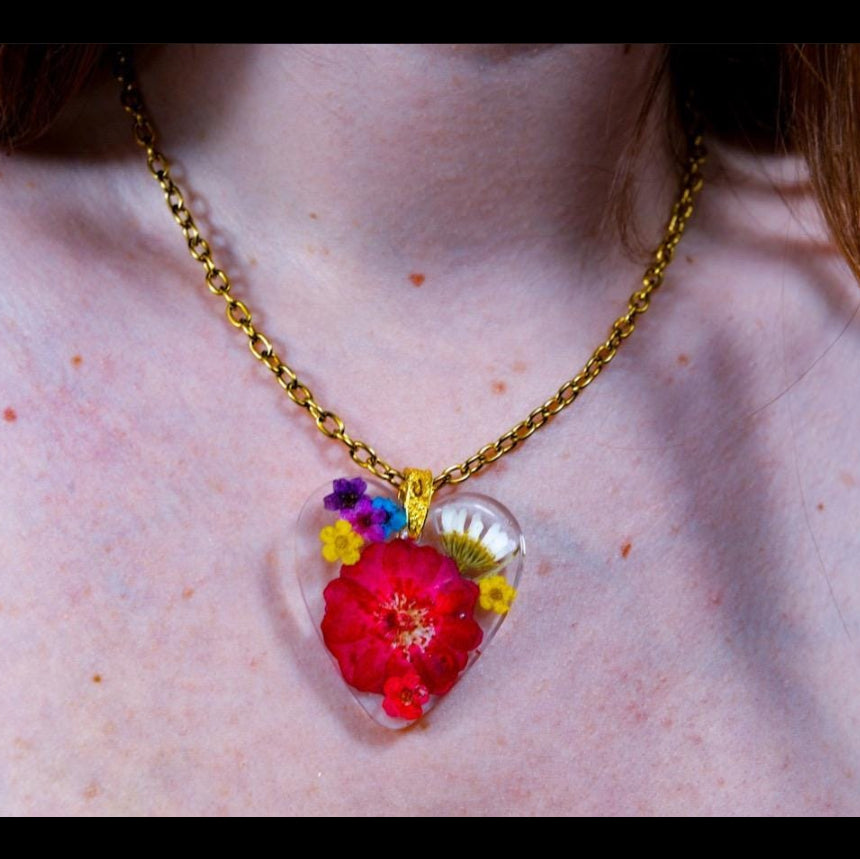 Necklace with a heart-shaped pendant featuring colorful flowers on a person's neck.